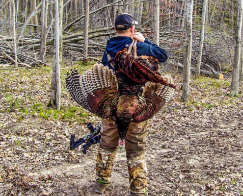 man carrying turkey after a successful turkey hunt